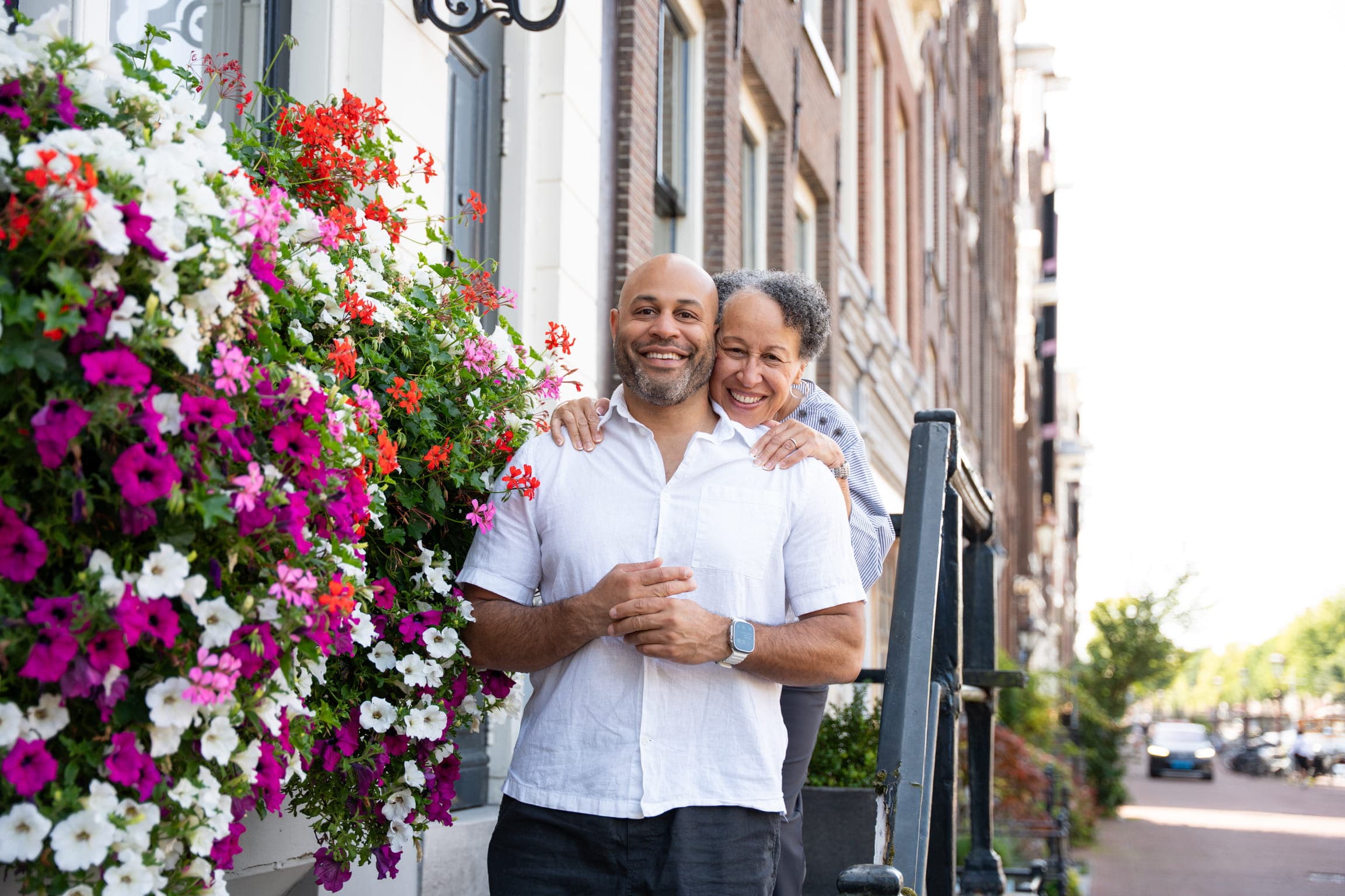 Jonathan and his mother, her arms around his shoulders, in front of a window box of petunias on an Amsterdam street